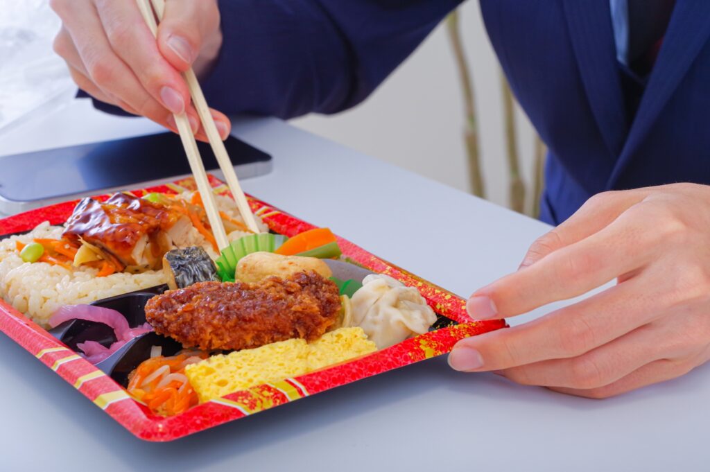 外食やコンビニ食で栄養が偏りやすい例として弁当を食べる手元の写真